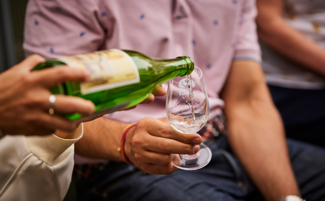 Sake being served, poured into a small wine glass.