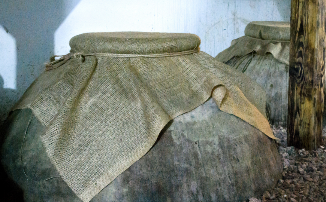 Clay pot sticking out from the ground, with the opening covered with some fabric
