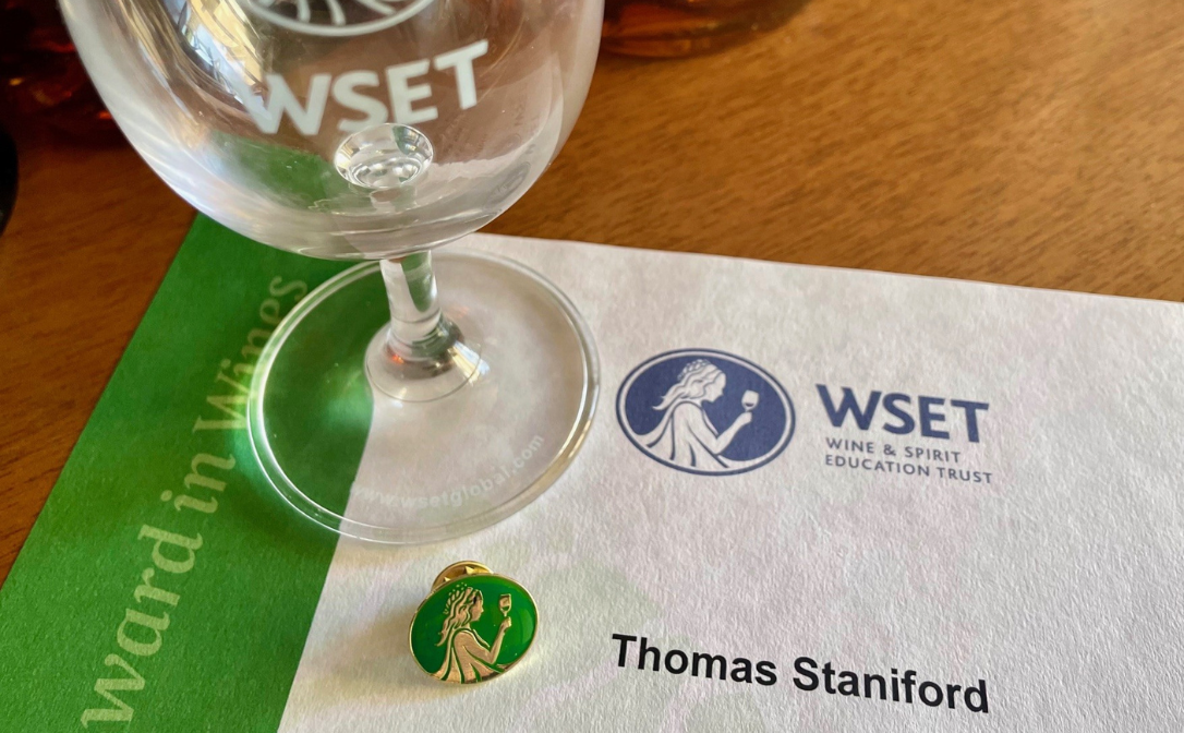 A white certificate with a bright green band down the side, with the words WSET and Thomas Staniford